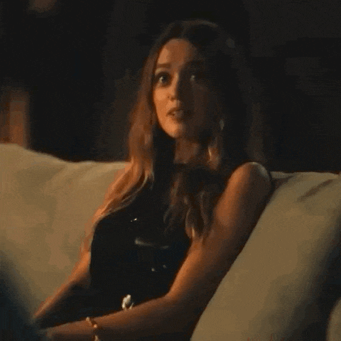 a woman is sitting on a couch in a dark room looking to the side .