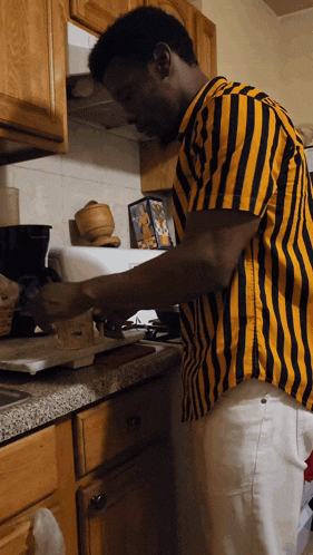 a man in a yellow and black striped shirt is preparing food
