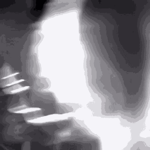 a black and white photo of a person 's face with a light coming out of it .