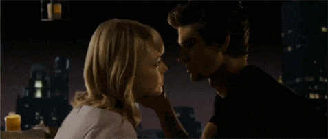 a man and woman are kissing in front of a city skyline at night .