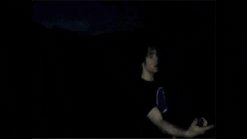 a young man wearing a black champion shirt is standing in the dark .