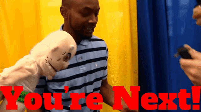 a man holding a puppet with the words " you 're next " on the bottom
