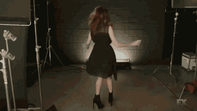 a woman in a black dress is dancing in front of a sign that says aya cash .