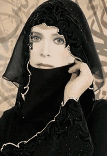 a woman wearing a black veil with pearls on the sleeves