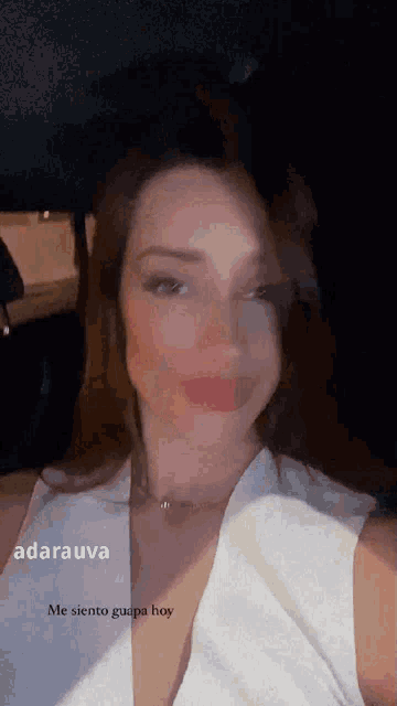 a woman in a white dress is taking a selfie with a caption that says me siento guapa hoy .
