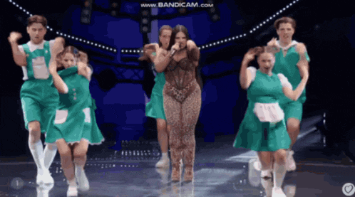 a woman in a leopard print jumpsuit is singing on a stage