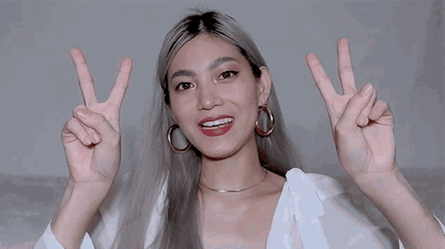 a woman with braces on her teeth is giving the peace sign
