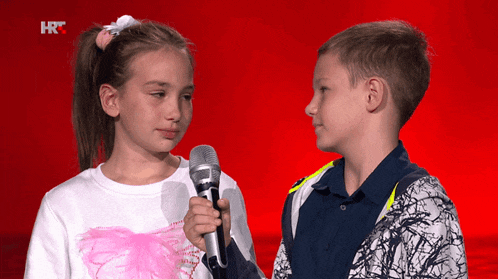 a boy and a girl are standing next to each other with a microphone in front of them with a red background that says hrc
