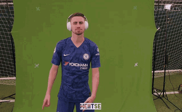 a man wearing headphones and a yokohama shirt stands in front of a green background