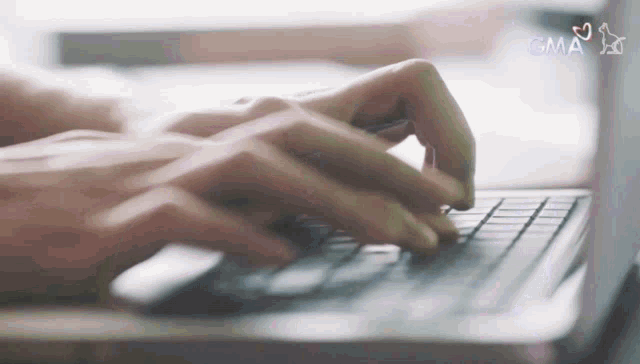a close up of a person typing on a laptop with the gma logo in the background