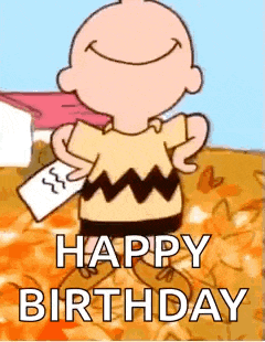 charlie brown is wearing a cape and holding a piece of paper and smiling .