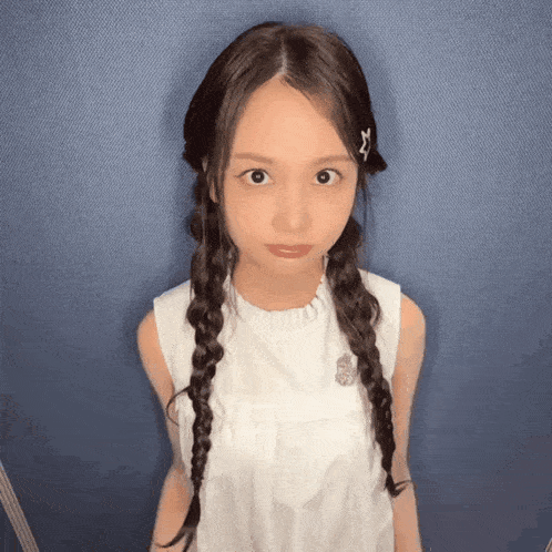a young girl with braids in her hair is wearing a white tank top