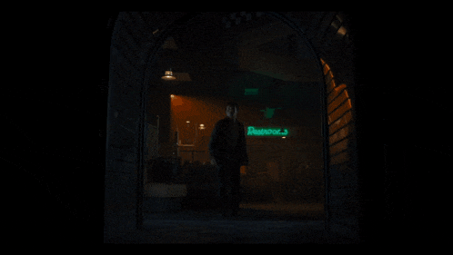 a man walks through a doorway with a neon sign that says photobooth