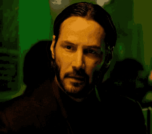 a man with a beard is looking at the camera in a dark room