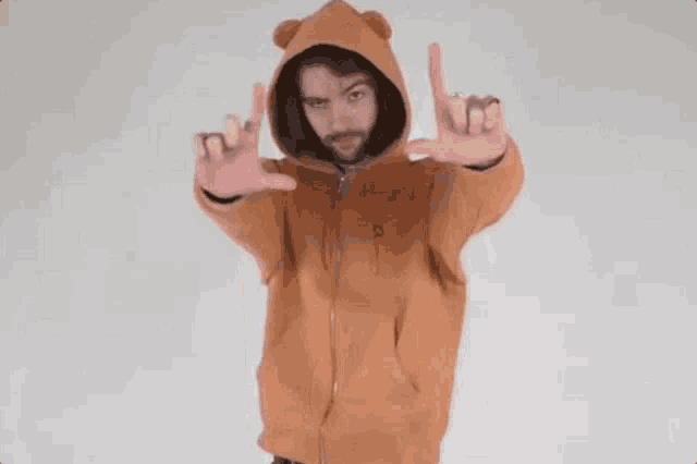 a man with a beard wearing a teddy bear hoodie is making a peace sign with his hands .