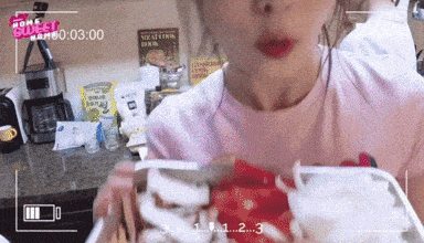 a woman in a pink shirt is eating food in a kitchen with the words home budget on the bottom left