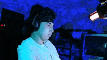 a man wearing headphones and a headband is sitting in front of a computer screen with a youtube logo in the corner