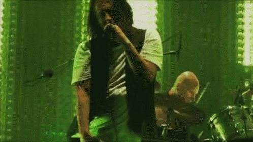 a man singing into a microphone in front of a drum set