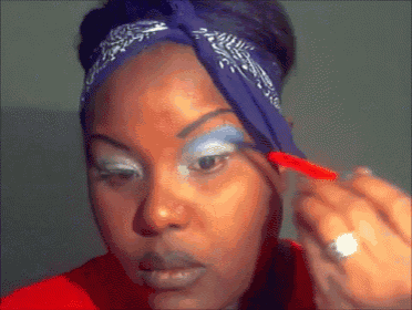 a woman wearing a blue bandana is applying makeup