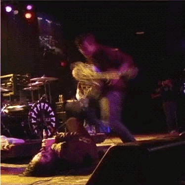 a man in a purple shirt is playing a guitar