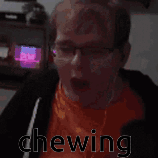 a man with glasses and an orange shirt is chewing