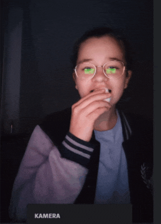 a girl wearing glasses and a jacket with the word kamera on the bottom right