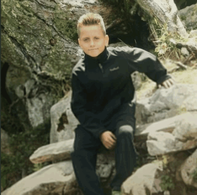 a boy wearing a black jacket with the word columbia on the front