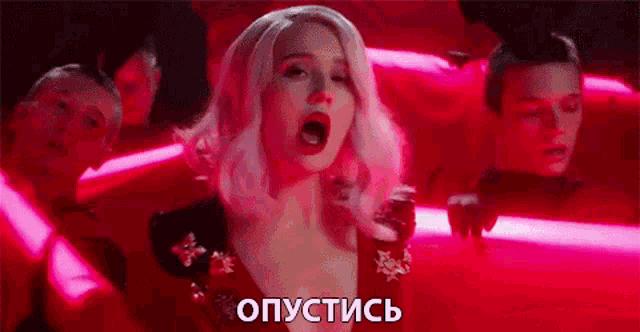 a woman with pink hair is singing in front of a group of men in a red room .