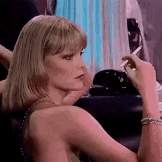 a woman is smoking a cigarette in a room while looking at the camera .