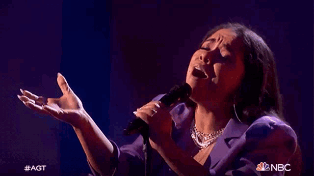 a woman singing into a microphone on nbc