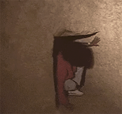 a person is standing upside down in front of a wall with a foreign language written on it .