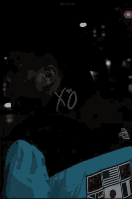 a man is wearing a jacket with flags on it and the word xo on his neck