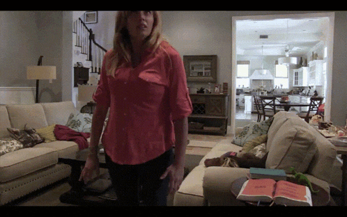 a woman in a red shirt stands in front of a couch