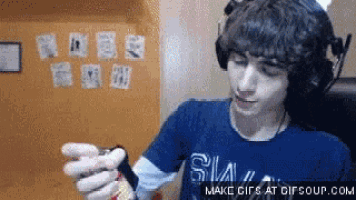 a man wearing headphones and a blue shirt is holding a can of soda .