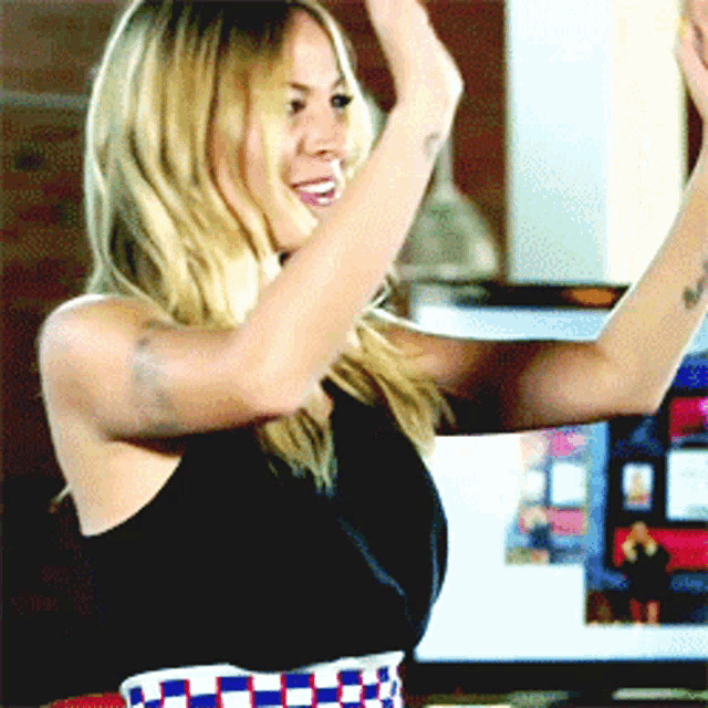 a woman in a black tank top is dancing