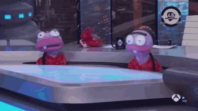 two cartoon characters are sitting on a table in front of a sign that says a comunicacion