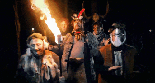 a group of people dressed in costumes holding a torch