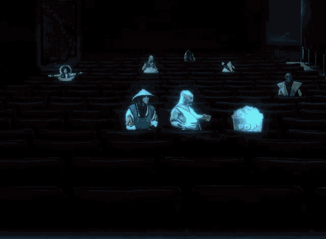a group of people sitting in a dark auditorium with a bucket of popcorn behind them