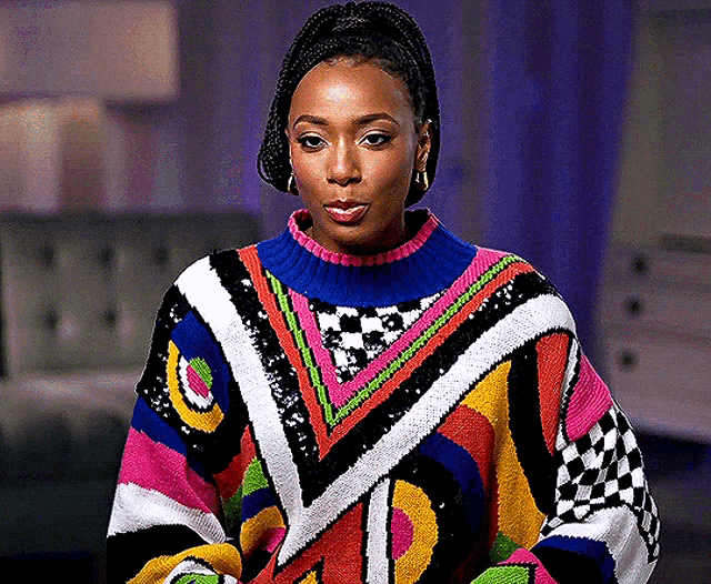 a woman wearing a colorful sweater is looking at the camera .