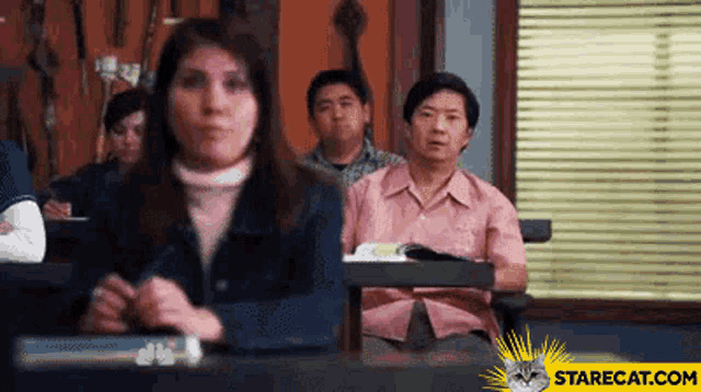 a group of people are sitting in a classroom with the website starecat.com visible in the corner