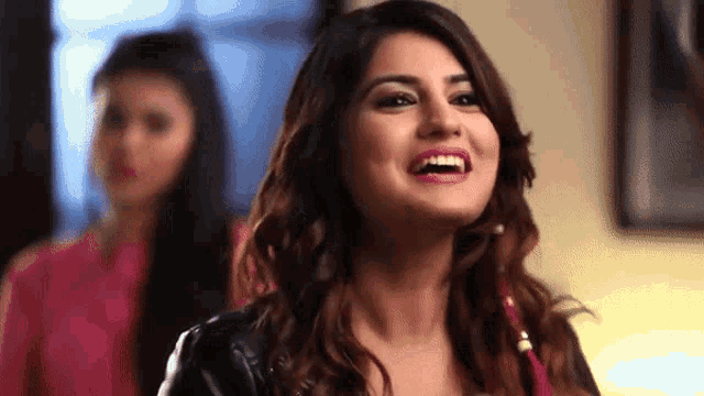 a close up of a woman laughing with another woman behind her .