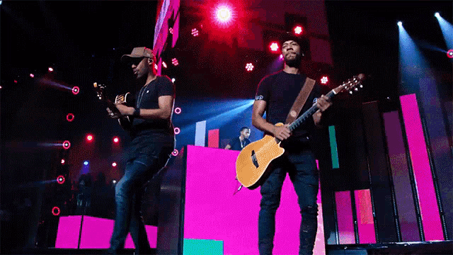 a man playing a guitar and another man playing a guitar on a stage