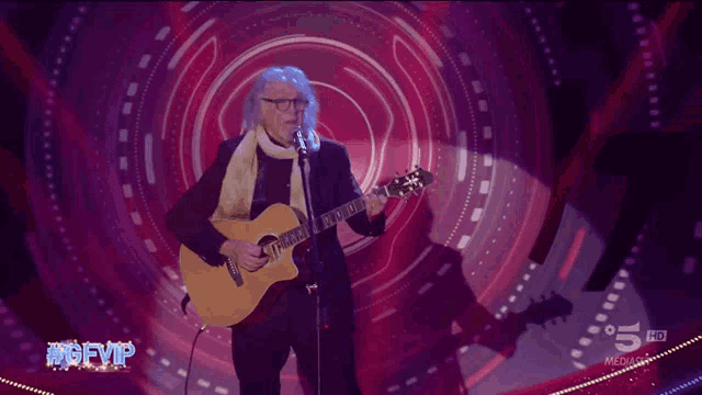 a man singing into a microphone while playing a guitar in front of a screen that says #gfvp