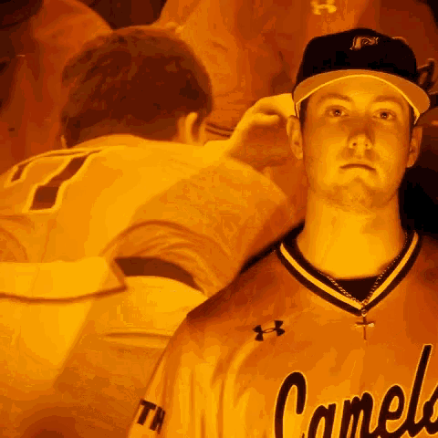 a man wearing a jersey that says camels stands in front of a crowd