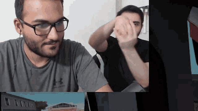 a man wearing glasses and an under armour shirt looks at a computer screen