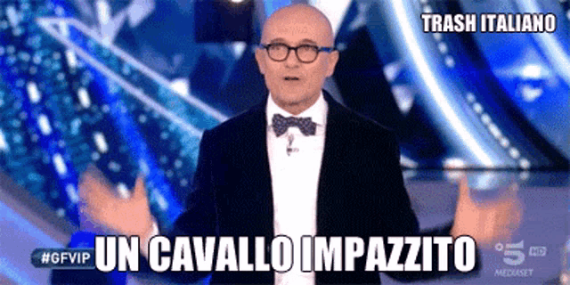 a bald man wearing glasses and a bow tie stands in front of a blue background with the words trash italiano on it