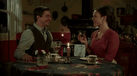 a man and woman sit at a table with a candle