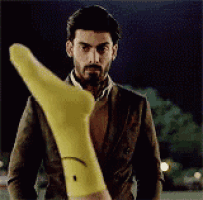 a man in a suit is holding a yellow socks with a smiley face on it .