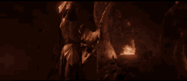 a man is holding a sword in a dark room .