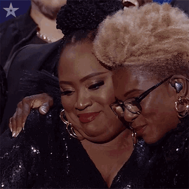 two women are hugging each other while wearing glasses and earrings .